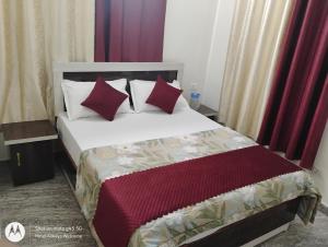 a bedroom with a large bed with red pillows at Hotel Always Welcome in Nākuri