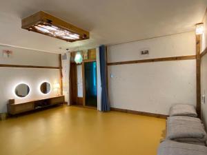 an empty room with a yellow floor and a couch at Architect's Cat Hanok - Sindal House Gyeongju in Gyeongju +16 photos