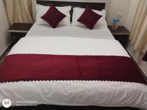 a bed with red and white blankets and pillows at Hotel Always Welcome in Nākuri