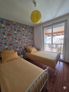 a bedroom with two beds and a wall covered in flowers at Gite de la Sauvetat in Auvillar