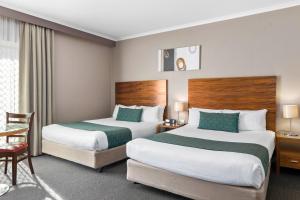a hotel room with two beds and a chair at Quality Hotel Dickson in Canberra