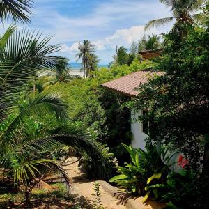 atropical garden with a house and palm trees at Mangrove Beach Houses in Srithanu