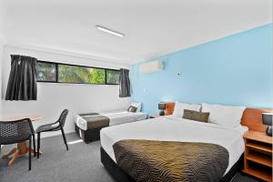 a hotel room with two beds and a table and chairs at Econo Lodge Waterford in Loganlea