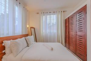 a bedroom with a white bed with a large window at Marahaba Holiday Suites Ground Floor 1BR 5 Min Drive to Nomad Beach in Ukunda +20 photos
