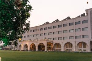 a large white building with a lawn in front of it at Hotel Aamodh in Lucknow