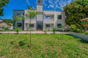 a house with a palm tree in the yard at Marahaba Holiday Suites Ground Floor 1BR 5 Min Drive to Nomad Beach in Ukunda