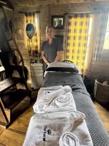 a woman standing next to a bed with towels at The Karal cabin in Canterbury
