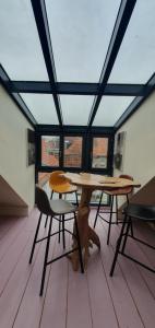 a dog sitting under a table in a room with windows at Maison PARAGONE in Bergues