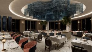 a restaurant with tables and chairs and a large chandelier at Merit Crystal Cove Hotel Casino & SPA in Kyrenia