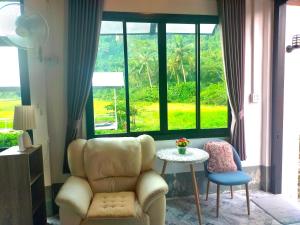 a living room with a chair and a table and a window at Good View Guest House in Phatthalung