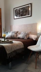 a bedroom with a large bed and a white chair at Apartamento Los Leones in Córdoba