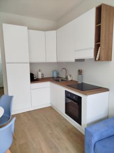 a small kitchen with white cabinets and a blue couch at ClaMar Apart Hotel in Porto Ercole +7 photos
