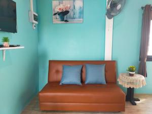 an orange couch with two blue pillows in a room at Good View Guest House in Phatthalung