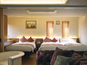 a hotel room with three beds and a couch at The GOAT AWAJI in Kusumoto