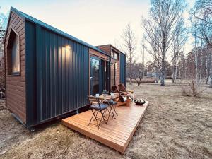 a tiny house with a table and chairs on a deck at Stockholm Archipelago by Tiny Away in Fagerdala +10 photos