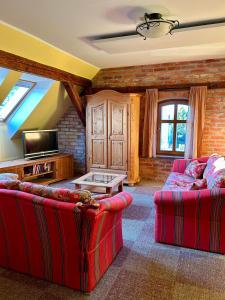 a living room with two red couches and a tv at Falkenwohnung in Gommern