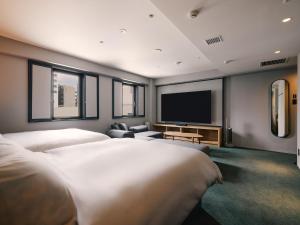 a hotel room with two beds and a flat screen tv at BASE LAYER HOTEL Nagoya Nishiki in Nagoya