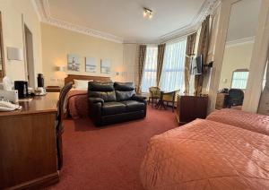 a hotel room with a bed and a chair and a desk at Welbeck Hotel & Apartments IOM in Douglas