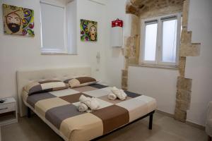 two beds in a bedroom with two windows at Kalsa’s House Noto in Noto