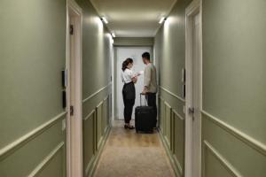 a man and woman standing in a hallway with a suitcase at Residenza Ximenes Hub in Palermo