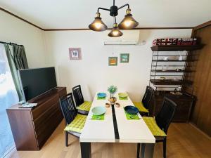 a dining room with a table with chairs and a television at 清場Kiyoba in Kawaguchi