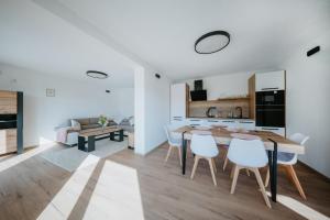 a kitchen and living room with a wooden table and chairs at Kotva By Momoland - Apartmán in Ružiná