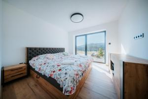 a bedroom with a bed and a large window at Kotva By Momoland - Apartmán in Ružiná