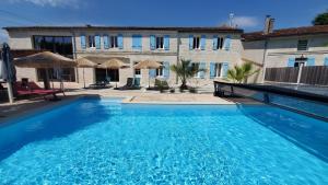 a large blue swimming pool in front of a building at Les Cuves - Saintes - Chambres d'hôtes et gîte in Saintes