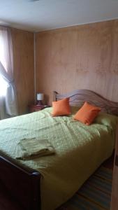 a bedroom with a bed with two orange pillows at Chacra Don Benito Chonchi in Chonchi