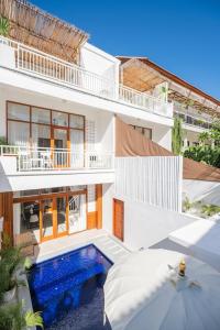 a white house with a swimming pool and an umbrella at Villa OG Cruz in Canggu