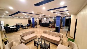 a large room with couches and a table with a person at Hotel Five Rivers - 2 Min to Allama Iqbal International Airport, Lahore in Lahore