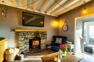 a living room with a fireplace and a tv on the wall at Portamaggie Cottage in Portpatrick