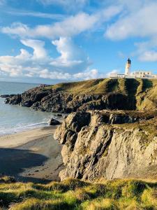 a lighthouse on top of a cliff next to the ocean at Portamaggie Cottage in Portpatrick +10 photos