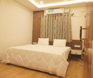 a bedroom with a bed with white sheets and a window at Dayanand Residency in Chitradurga