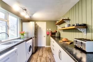 a kitchen with a sink and a refrigerator at Portamaggie Cottage in Portpatrick