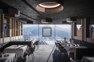 ein Restaurant mit Tischen und Stühlen und einem großen Fenster in der Unterkunft Hotel Hubertus in Olang