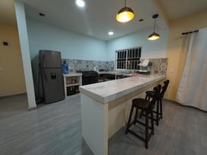 a kitchen with a large white counter and two stools at Casa ilusion Tuxpan Veracruz in Tampamachoco +8 photos