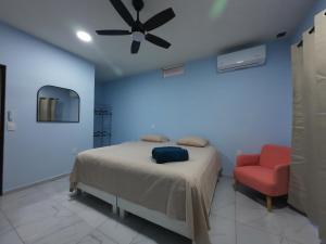 a bedroom with a bed and a ceiling fan and a red chair at Casa ilusion Tuxpan Veracruz in Tampamachoco