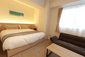 a bedroom with a bed and a couch and a window at muniyuitsu 宮古島 spa&park in Miyako-jima
