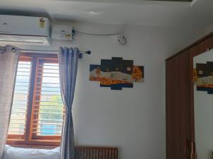 a bedroom with a window and a curtain at Dayanand Residency in Chitradurga +3 photos