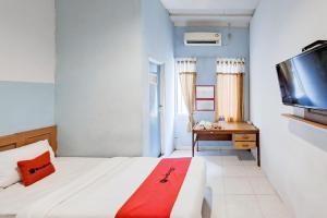 a bedroom with a bed and a desk and a tv at RedDoorz at Arca Hostel Lampung in Lampung