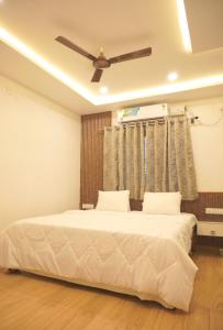 two beds in a bedroom with a ceiling fan at Dayanand Residency in Chitradurga