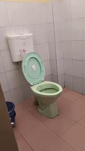 a bathroom with a toilet with a green seat at Hotel Silver Dragon, NK Darranga in Darranga