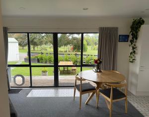 a room with a table and chairs and a large window at Protea Cottage in Masterton