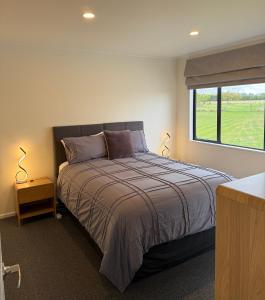 a bedroom with a large bed and a window at Protea Cottage in Masterton