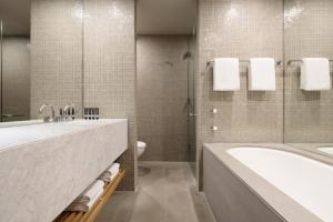 a bathroom with a tub and a sink and a toilet at Hotel Realm in Canberra