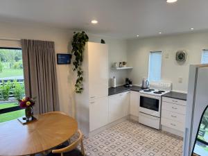 a kitchen with white cabinets and a table and a dining room at Protea Cottage in Masterton +15 photos