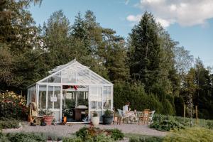 a greenhouse in a garden with a person sitting at a table at Kansjerf Gård in Bromary +33 photos