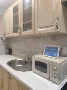 a kitchen counter with a microwave and a sink at PortStreet apartamenti in Liepāja