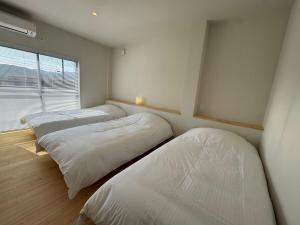 two beds in a room with a window at 5名様まで宿泊可能 四万十市下田の一棟貸し宿 明の宿 akari in Shimanto